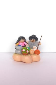 Pesebre artesanal con figuras campesinas, animales y flores sobre base decorativa.